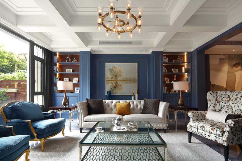 客廳的立面有兩處裝飾柜，兩面相對稱呼應。裝飾上運用涂料和護墻的手法，使空間豐富感更強。深灰色地磚一鋪到底，從客廳一直延伸到餐廳，并鋪上米灰色地毯做裝飾，使空間色彩更加柔和。