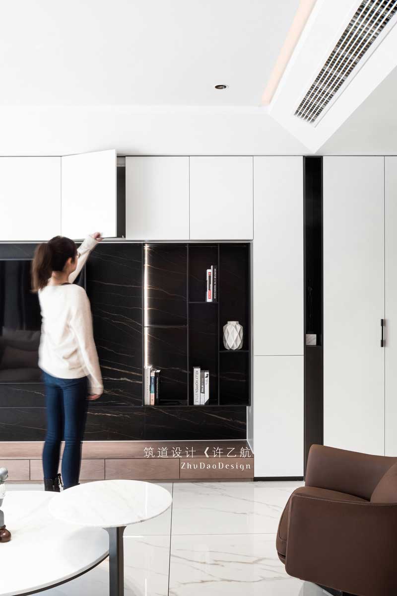 設計師拋棄傳統客廳的固有印象,將儲物柜與電視背景墻相結合,不僅增加了空間的儲物空間,在自然柔和的燈帶的襯托下,深灰色的啞光金屬條與深色大理石背景更有層次感,也成為了公共空間的一亮點所在。 設計師拋棄傳統客廳的固有印象,將儲物柜與電視背景墻相結合,不僅增加了空間的儲物空間,在自然柔和的燈帶的襯托下,深灰色的啞光金屬條與深色大理石背景更有層次感,也成為了公共空間的一亮點所在。